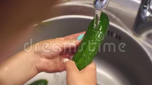 一个女人在厨房水槽里洗新鲜黄瓜的特写镜头视频的预览图