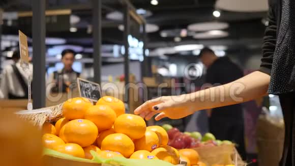 年轻的混合种族妇女采摘橘子水果在杂货店超市商店4K视频的预览图