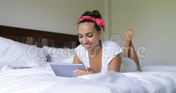 年轻女子用平板电脑美女躺在床上卧室早上上网聊天视频的预览图