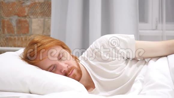 红头发的胡子男躺在床上睡觉放松视频的预览图