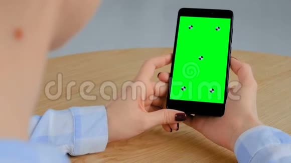 女人拿着黑色智能手机空白的绿色屏幕色度关键概念视频的预览图