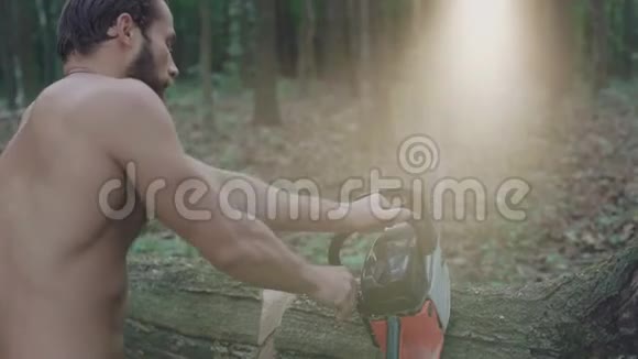 英俊的大胡子伐木工人在森林里用电锯锯树4K视频的预览图