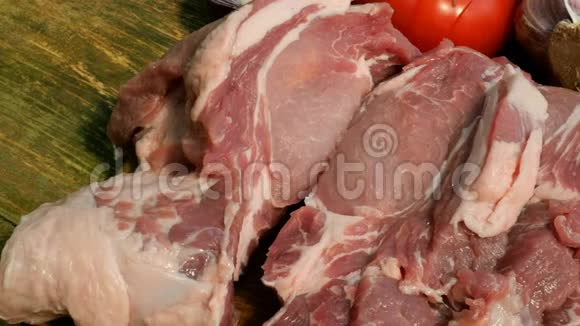 生肉牛排是从一大块猪肉或牛肉中在木切割板上切出来的视频的预览图