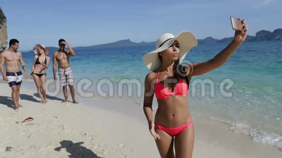 沙滩上的女人手持手机打电话给人们拍照微笑的年轻游客组视频的预览图