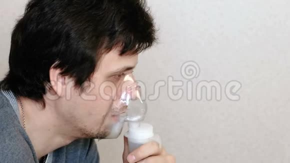 使用雾化器和吸入器进行治疗年轻人通过吸入面罩和咳嗽吸入侧视视频的预览图