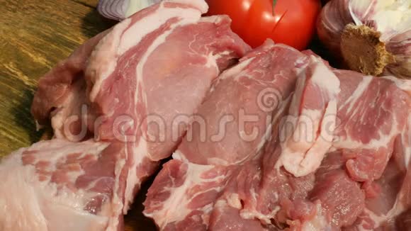 生肉牛排是从一大块猪肉或牛肉中在木切割板上切出来的视频的预览图