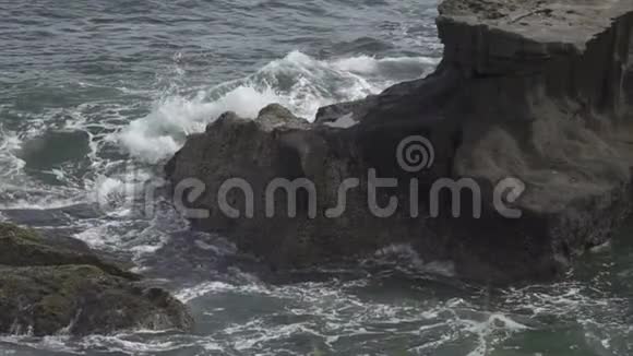 热带海洋的海岸在阳光明媚的日子里波浪在海岸上流淌着黑色的石头缓慢的运动视频的预览图