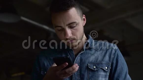 一个年轻人在黑暗的大厅里用电话视频的预览图