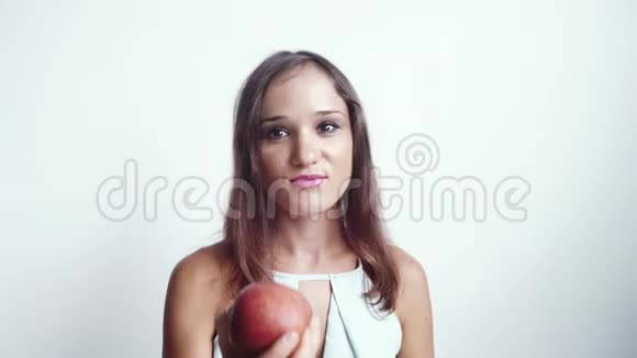 美丽的年轻微笑的女人吃红苹果水果慢动作孤立在白色背景上3840x2160视频的预览图