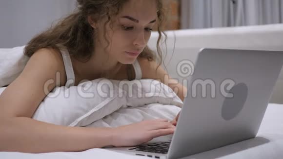 床上兴奋的女性在笔记本电脑上庆祝成功视频的预览图