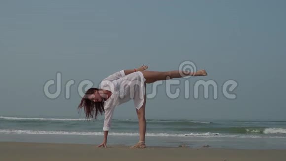 一个漂亮的女孩正在海滩上练习瑜伽4K视频的预览图
