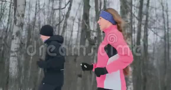 青年男女在冬林晨跑一个穿宽松夹克的女人一个穿黑色夹克的男人在跑步视频的预览图