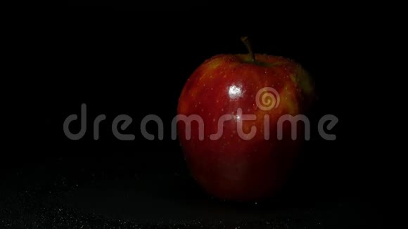 黑色背景上的新鲜红苹果一小滴水顺着苹果流下视频的预览图