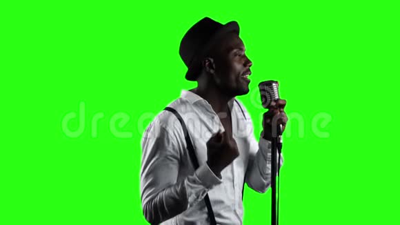 男歌手在营业额的一半唱歌成麦克风和舞蹈绿色屏幕慢动作关门视频的预览图