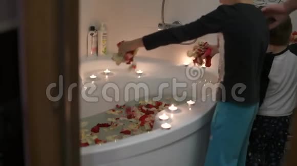 爸爸和两个儿子为妈妈准备一个惊喜他们在浴室点燃蜡烛洒满玫瑰花瓣视频的预览图