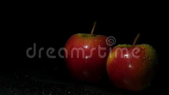 清澈多汁的苹果在黑暗中飞溅的水中视频的预览图