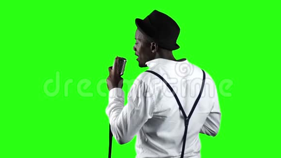 歌手从后面的视图唱成复古麦克风并在它附近跳舞绿色屏幕慢动作关门视频的预览图