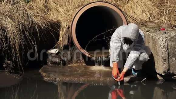 穿着生物危险服和防毒面具的人检查外面的水污染视频的预览图