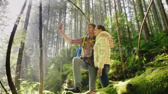 一对爱着背包旅行者的夫妇在森林里拍照朝阳的光芒美丽视频的预览图
