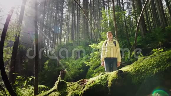 一个穿着羽绒服和背包系鞋带的女旅行者站在树林里风景如画视频的预览图