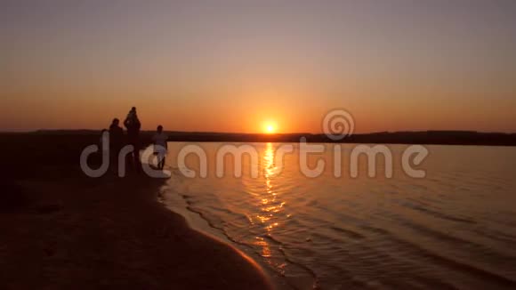 一家人在夕阳红下沿着海岸散步慢动作视频的预览图