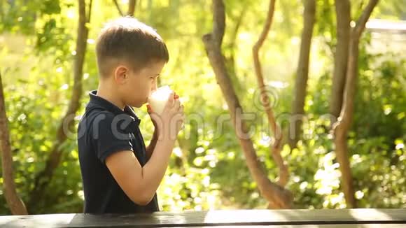 一个男孩在大自然的桌子上喝牛奶视频的预览图
