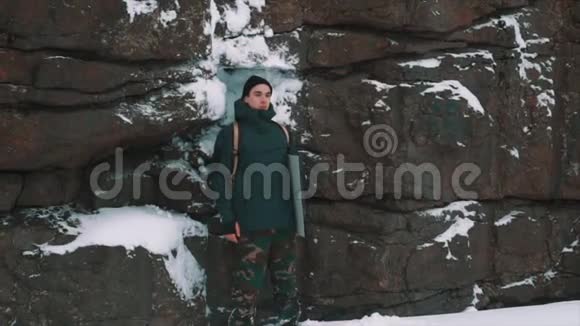 一个年轻人站在被雪覆盖的岩壁前视频的预览图