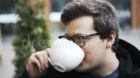 一个戴眼镜的家伙喝着咖啡听着朋友的声音笑着视频的预览图
