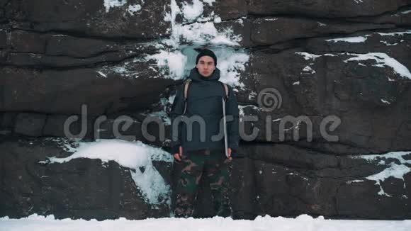 年轻人在白雪覆盖的岩壁前大笑视频的预览图