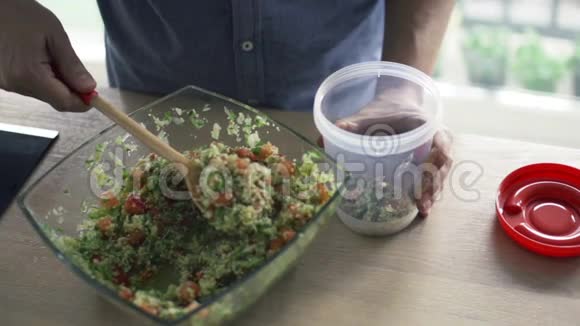 男人把沙拉放进厨房的塑料盒子里视频的预览图