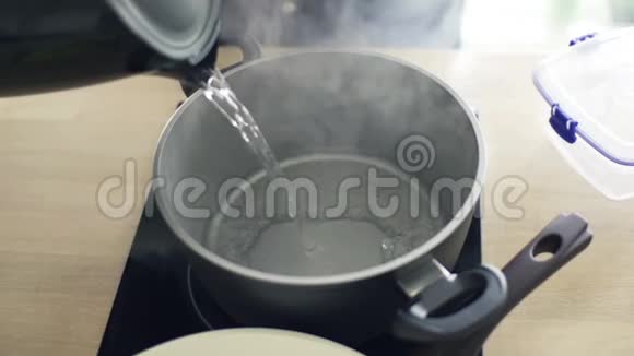 在厨房里用水壶把开水倒入锅中视频的预览图