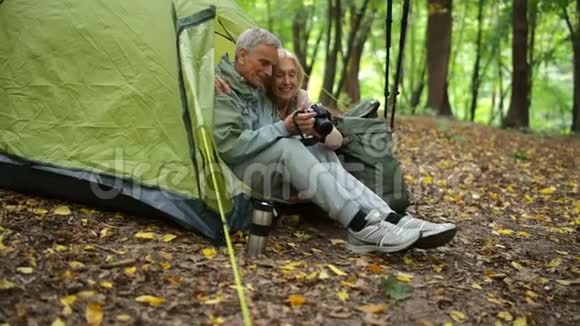 快乐的老夫妇在树林里看照片视频的预览图