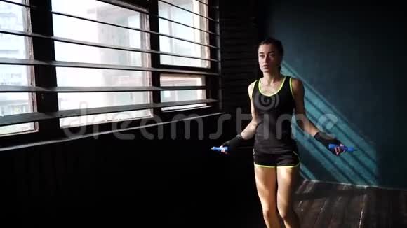 动作缓慢的年轻严肃的女拳击手裹着双手热身在健身房跳绳视频的预览图