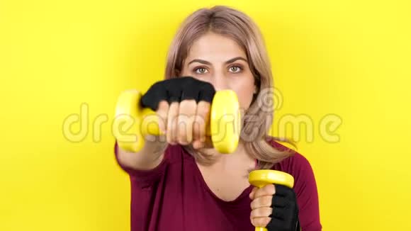 女子黄色背景练习哑铃运动视频的预览图