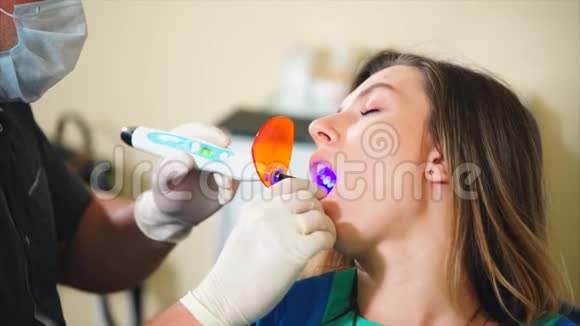 现代牙科治疗医生在女性牙齿使用紫外线灯视频的预览图