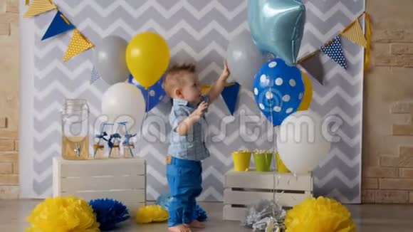 一个蹒跚学步的孩子笑着打着绑好的气球视频的预览图