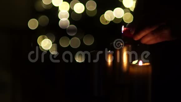 男性手点燃蜡烛用模糊的圣诞灯光背景关闭三支燃烧的蜡烛视频的预览图
