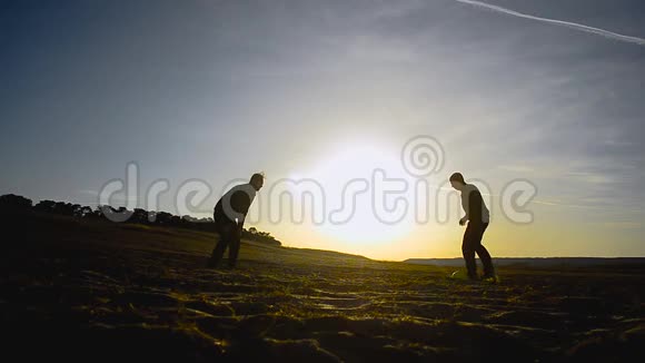 春天两个男人在沙滩上踢足球在阳光下在沙滩上踢足球视频的预览图