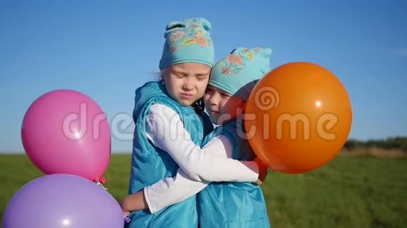两个双胞胎姐妹拥抱亲吻孩子们拿着气球视频的预览图