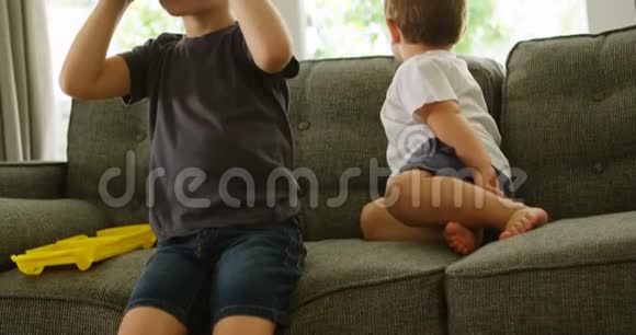 男孩坐在沙发上而兄弟则使用虚拟现实耳机4k视频的预览图