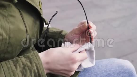 年轻女子在公园的长凳上擦眼镜视频的预览图