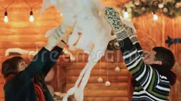 一男一女在童话般的房子背景下扔人造雪拥抱圣诞节和新年主题视频的预览图