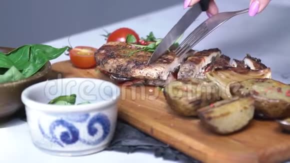 一个妇女用刀叉在木板上切肉卷视频的预览图