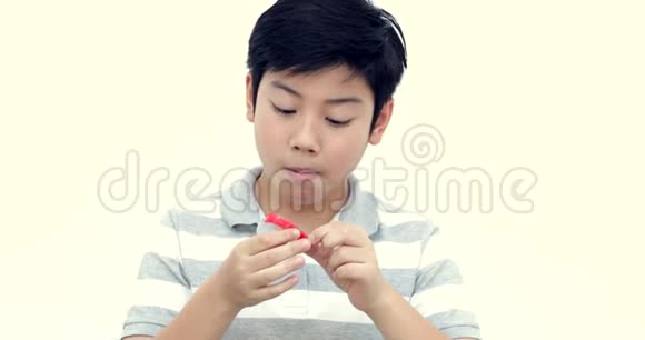 小亚洲男孩吃果冻白色墙壁背景微笑视频的预览图