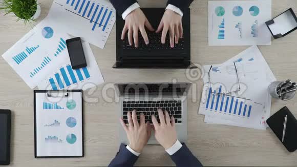 商人的手在对面的笔记本电脑上打字有趣的顶部视图视频的预览图