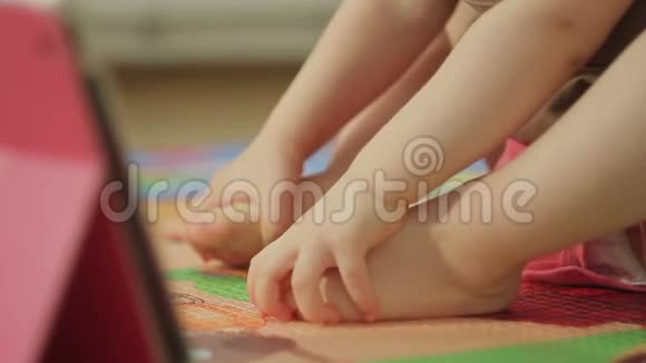 一个小女孩赤脚坐在电子平板电脑旁的特写镜头视频的预览图