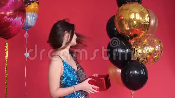 美丽的年轻女孩穿着闪闪发光的裙子捧着礼物视频的预览图