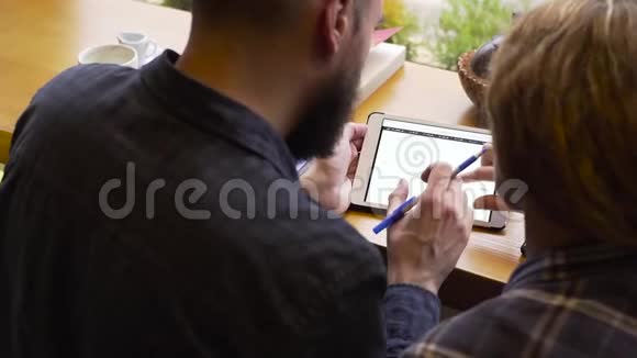 在一家咖啡馆里男人和女人在平板电脑上讨论经济表现视频的预览图