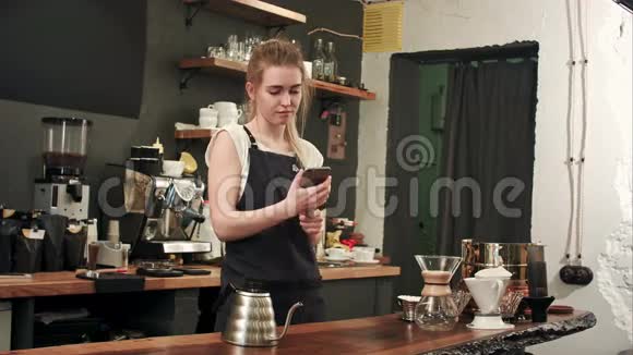 快乐的女咖啡师用智能手机在咖啡店自拍视频的预览图