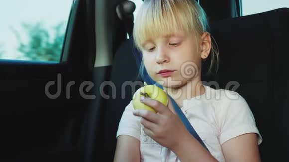 在路上吃零食女孩吃苹果坐在汽车后座视频的预览图